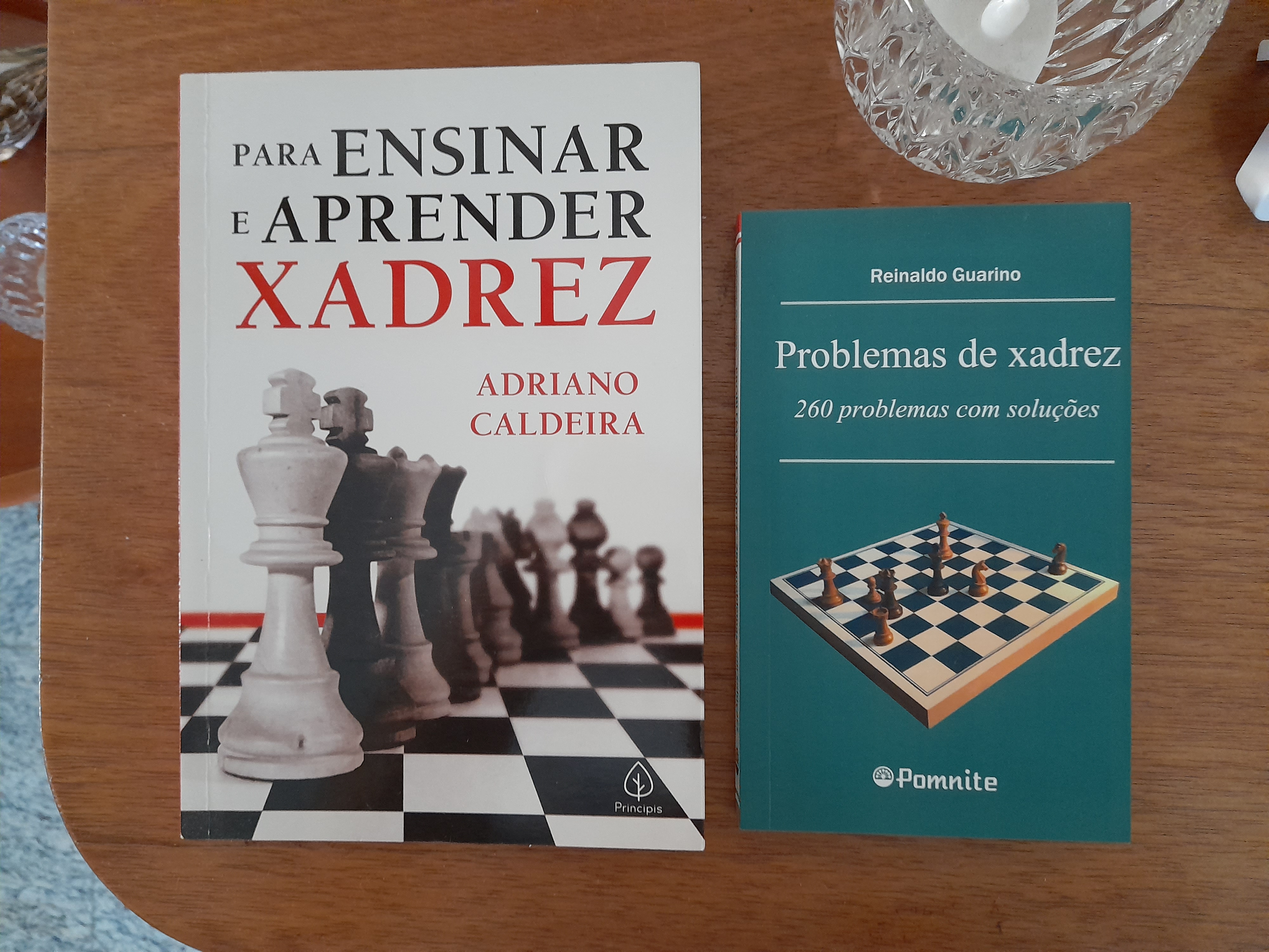 A stack of chess books on a wooden surface
